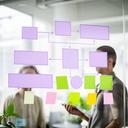 Process automation consultant planning RPA workflows with sticky notes and system diagrams on a glass wall